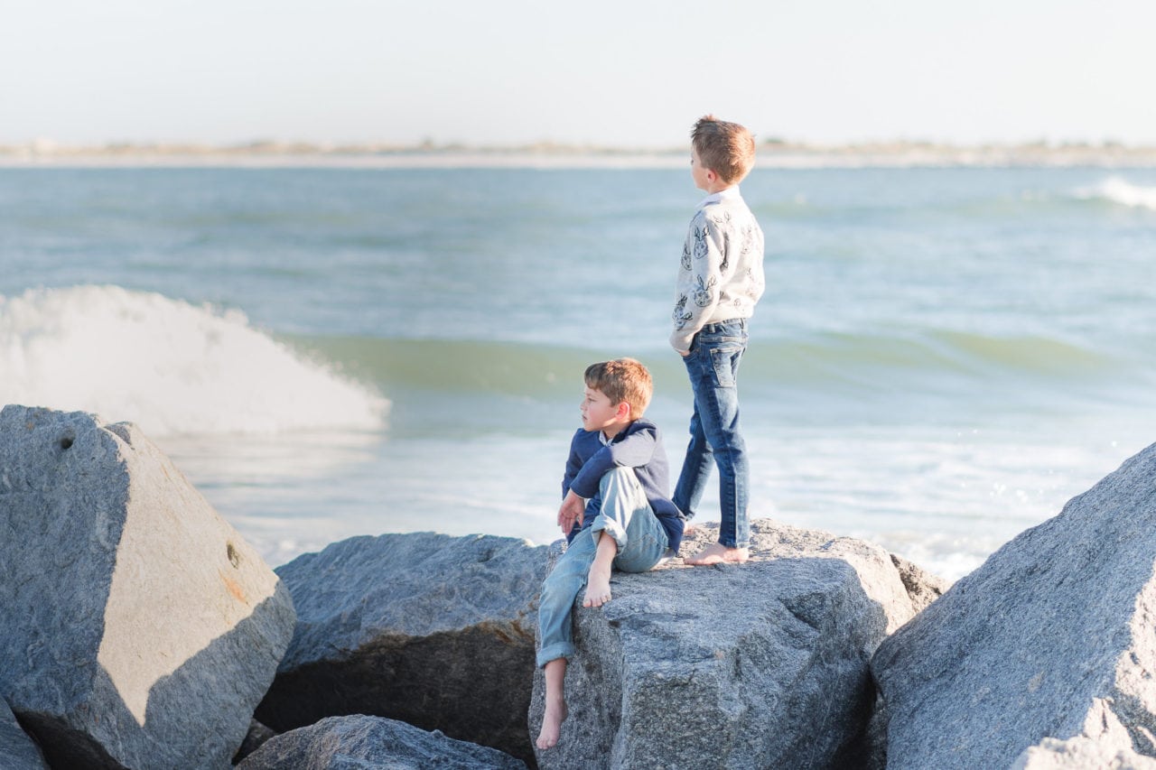 twin-boys-standing-on-rocks-facing-harbor